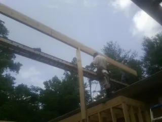 Carpenter setting a ridge beam over a new addition frame — Ice Dam Removal by Roofing Brothers in Grand Valley