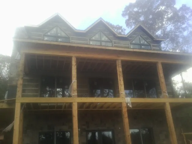 Dormers and porch framing on a large log home under construction — Roof Coating work by our crew in Grand Valley