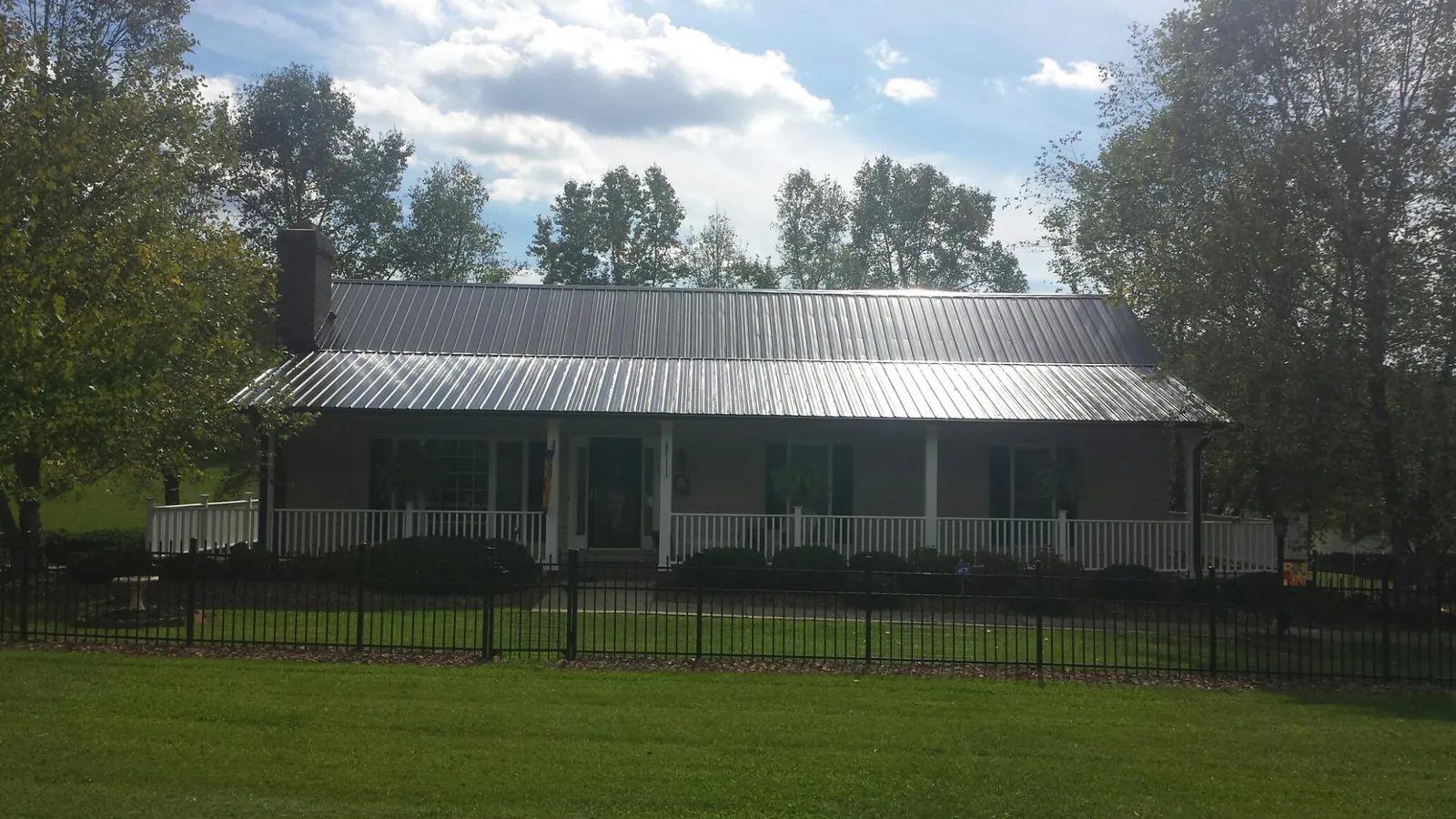 Gray metal roof on a brick ranch with a full width front porch — Gutter Guard Installation work by our crew in Grand Valley