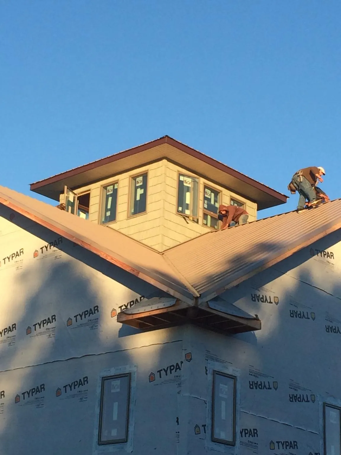 Roofers working around a rooftop cupola on a new metal roof at sunset — Roof Waterproofing in Grand Valley by Roofing Brothers